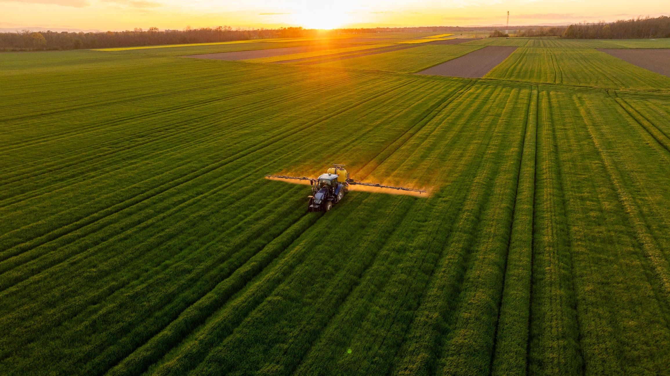 Landmaschine auf einem Feld bei Sonnenuntergang